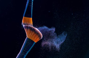 Siyah arkaplanda barut patlaması ile makyaj fırçası