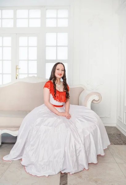 Piękna Kobieta Białej Czerwonej Średniowiecznej Sukience Siedzi Kanapie — Zdjęcie stockowe