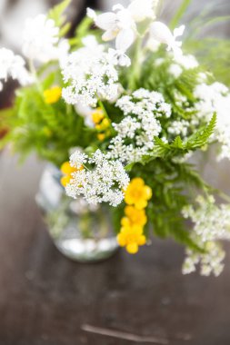 Buket çiçegi ve eski ahşap masa üzerinde çim ile natürmort