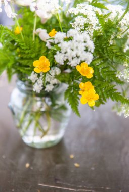 Buket çiçegi ve eski ahşap masa üzerinde çim ile natürmort