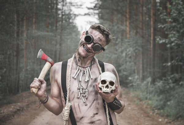 Cannibal Man in glasses with ax, skull and rope outdoor