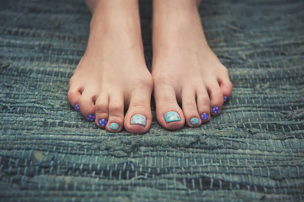 Woman feet with funny nails on the carpet