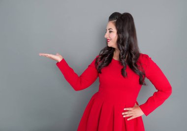 Bir şey elde gri arka plan üzerinde gösterilen mutlu artı boyutu kadın