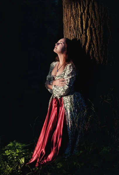 屋外の木の近くの緑の中世ドレスで美しい少女 — ストック写真