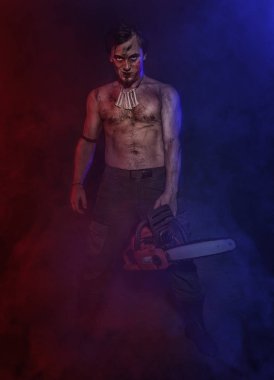 Kırmızı ve mavi sis içinde gülümseyen chainsaw korkunç adam. Cadılar Bayramı sahne