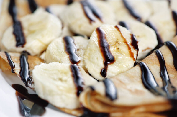 Тонкий вкусный блинчик с бананом и шоколадом на белой спине
