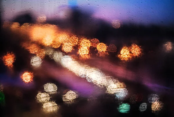 Blurry abstract background with defocused lights in city through — Stock Photo, Image