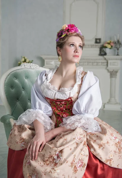 Piękna kobieta w staromodny sukienka średniowiecznej na kanapie — Zdjęcie stockowe