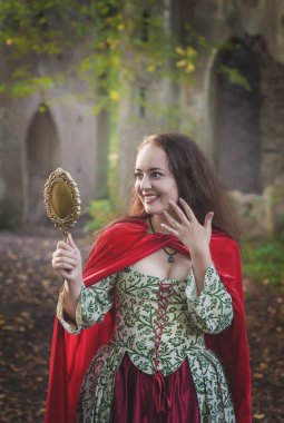 Ayna ile uzun ortaçağ elbise güzel gülümseyen kadın 