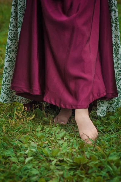 Pernas de mulher em vestido medieval longo andando no campo de verão — Fotografia de Stock