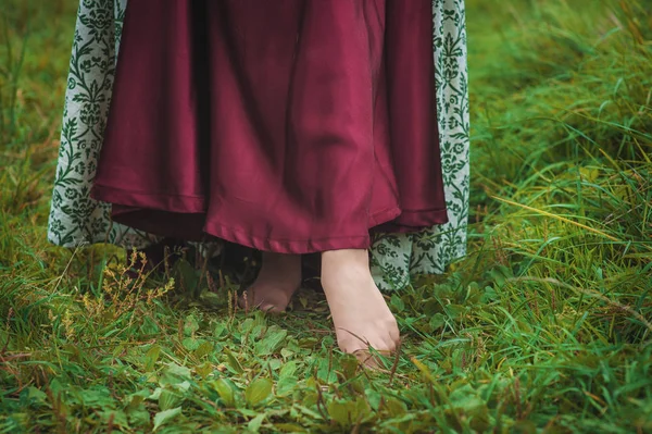 Beine einer Frau im langen mittelalterlichen Kleid, die im Sommerfeld spaziert — Stockfoto
