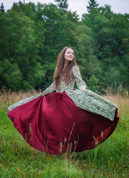 Mooie gelukkige vrouw in lange middeleeuwse jurk dansen — Stockfoto