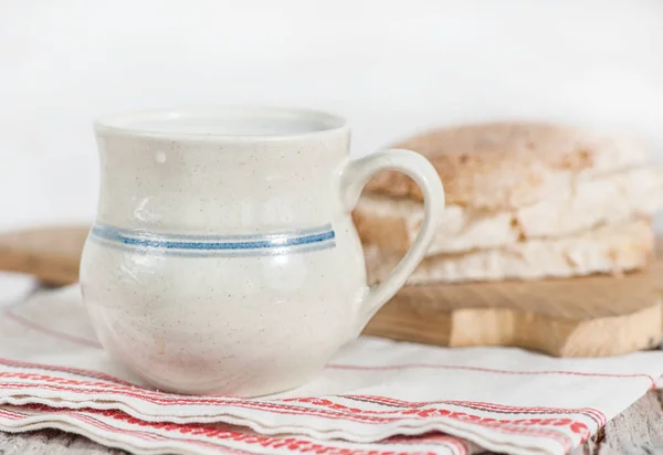 Slices of fresh bread and Cup of milk on the old table — Stock Photo, Image