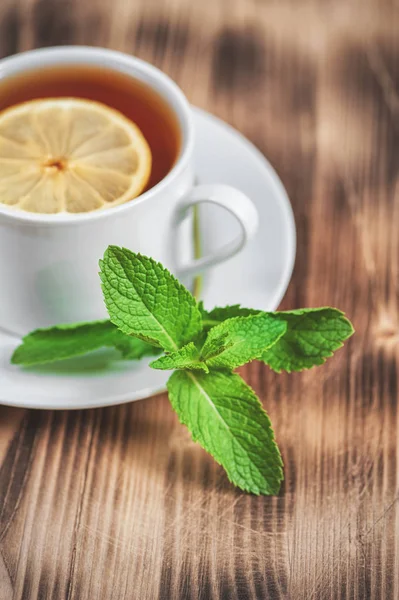 Tasse mit Tee, Minze und Zitrone auf dem alten Tisch — Stockfoto