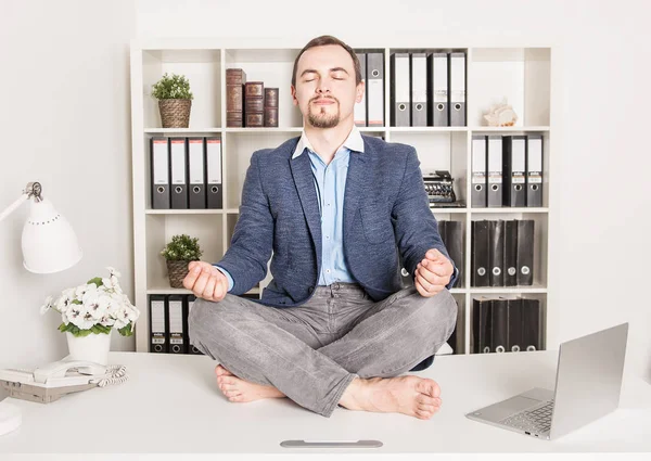 Handsome business man relax in lotus pose in office