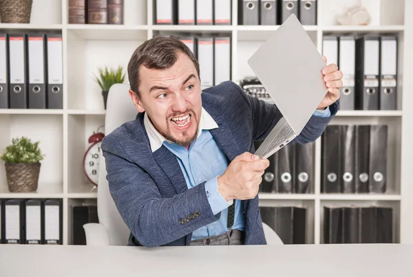 Un uomo d'affari arrabbiato che rompe un portatile. Concetto di stress — Foto Stock