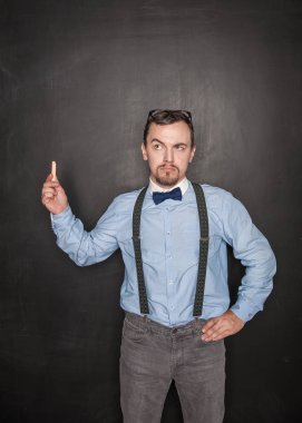 Tebeşirile düşünceli öğretmen tahtaya bakıyor 