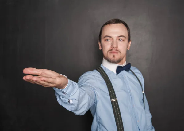 Knappe man die op iets op zijn hand toont op Blackboard — Stockfoto