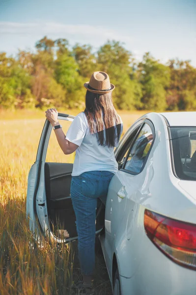 Junge Frau mit weißem Auto im Feld — Stockfoto