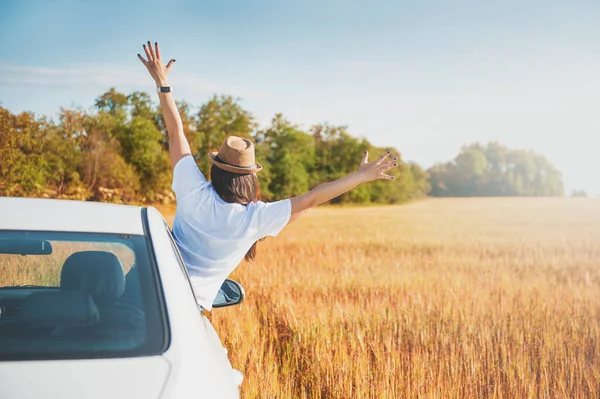 Junge Frau mit erhobenen Händen in weißem Auto auf dem Feld — Stockfoto