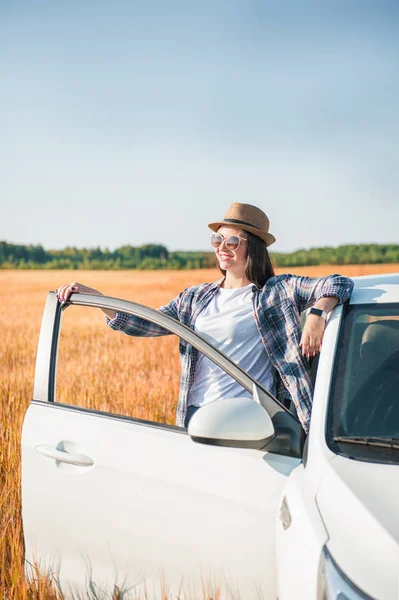 Schöne Frau mit weißem Auto auf dem Feld — Stockfoto