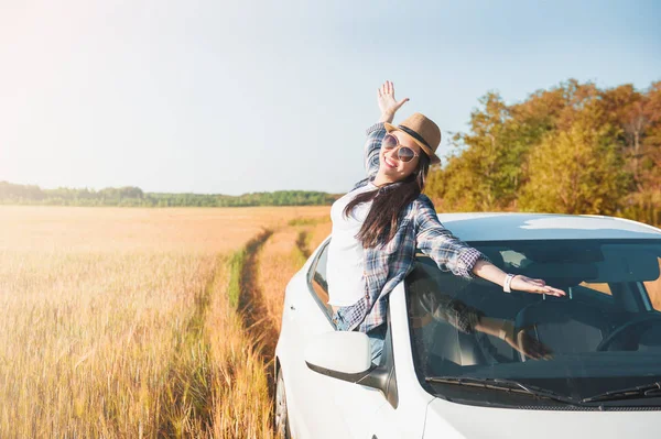 Junge Frau mit erhobenen Händen in weißem Auto auf dem Feld — Stockfoto