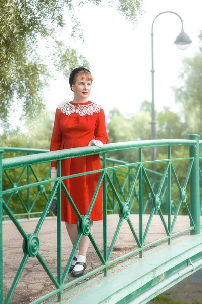 Beautiful woman retro style in red dress on the bridge — Stock Photo, Image