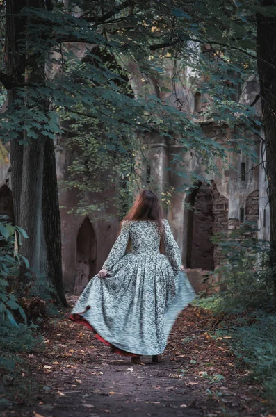 Beautiful girl in long medieval dress walk to abandoned castle — Stock Photo, Image
