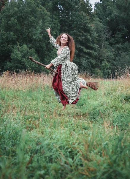穿着中世纪礼服的漂亮女人在扫把上飞翔 — 图库照片