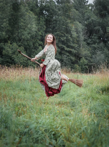 Vacker kvinna i medeltida klänning flyger på kvasten — Stockfoto