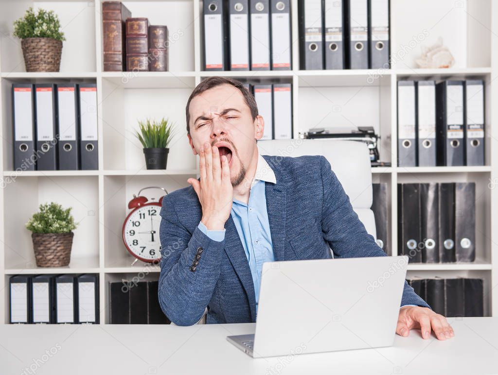 Bored business man yawning in office