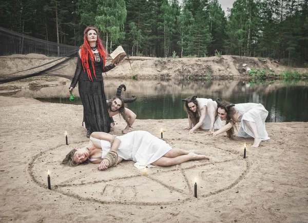 Belle sorcière faisant de la sorcellerie avec des démons à cornes et victime — Photo