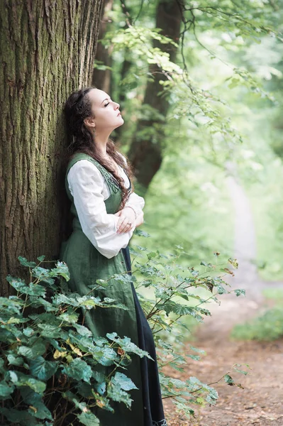 Bella donna in abito verde medievale vicino albero — Foto Stock