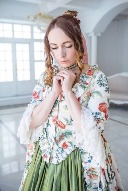 Yeşil uzun ortaçağ elbisesi içinde dua eden güzel bir kadının portresi. 