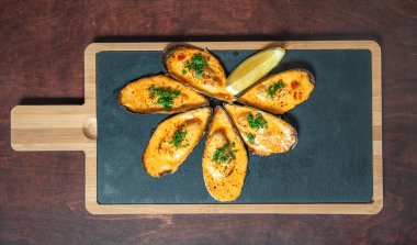 Kesme tahtasının üzerinde otlu ve limonlu lezzetli midye. Üst yaşam