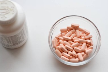 vitamin tabletleri üzerinde beyaz bir arka plan ile bir kase ve kavanoz tablet