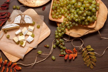 Kağıt ve ahşap masa üzerinde üzüm salkımı pişirme ile camembert peyniri