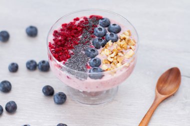 Sağlıklı kahvaltı kase: blueberry smoothie muz, ahududu, böğürtlen, tablo üzerinde fındık ile