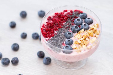 Sağlıklı kahvaltı kase: blueberry smoothie muz, ahududu, böğürtlen, tablo üzerinde fındık ile