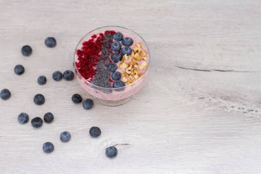 Sağlıklı kahvaltı kase: blueberry smoothie muz, ahududu, böğürtlen, tablo üzerinde fındık ile