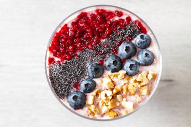 Sağlıklı kahvaltı kase: blueberry smoothie muz, ahududu, böğürtlen, tablo üzerinde fındık ile