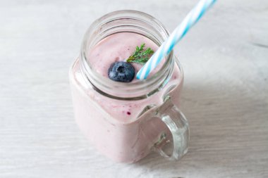 blueberrie güler yüzlü bir kavanoz kupa masada bir saman ile