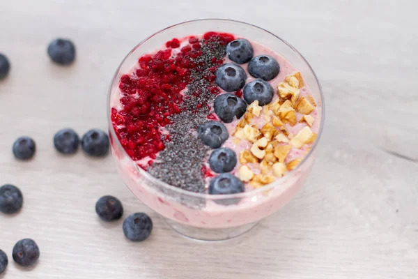 Sağlıklı kahvaltı kase: blueberry smoothie muz, ahududu, böğürtlen, tablo üzerinde fındık ile