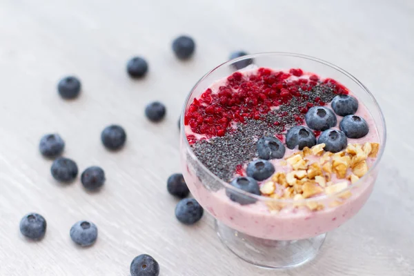 Sağlıklı kahvaltı kase: blueberry smoothie muz, ahududu, böğürtlen, tablo üzerinde fındık ile