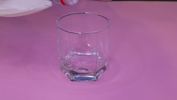 Versare il latte in un bicchiere su sfondo rosa — Video Stock