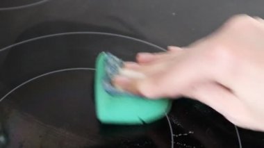 Kadın sobayı yıkıyor. Yeşil süngerli eller Indüksiyon sobasını yıkıyor. Evi temizliyorum.