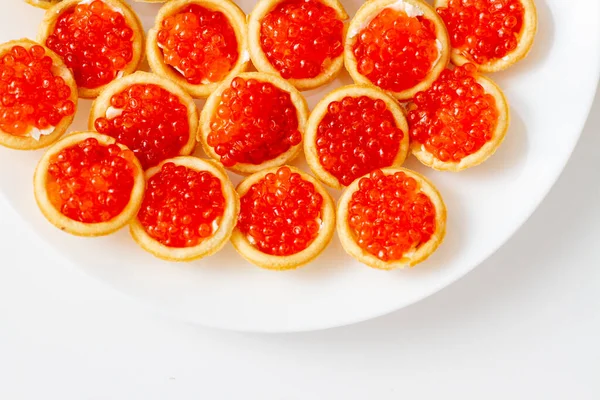 Tartlets with red caviar on white plate. Red caviar top view.