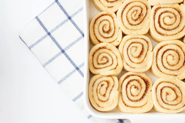 Çiğ tarçınlı rulo, kareli bir peçetede fırın kabında..