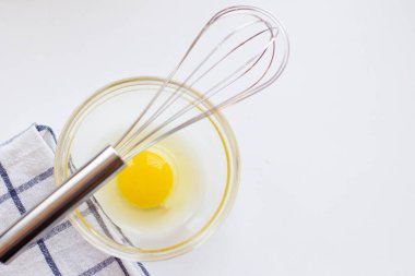 Cam kasede yumurtaları metal çırpıcı ve peçeteyle karıştırmak. Düz yatış, üst görünüm.