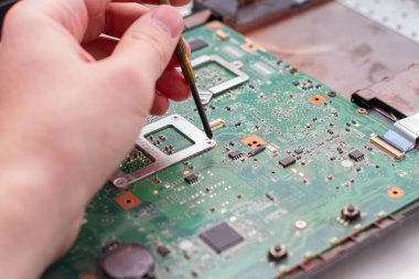 Ana bilgisayar elektroniğindeki mikro devreyi tamir eden teknisyen. Bilgisayar ana kartı